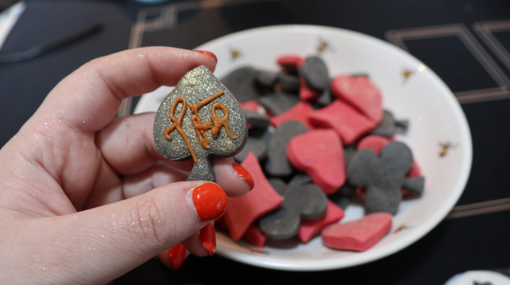 Hand-decorated card-suit biscuits with hearts, clubs, diamonds and spades visible in a bowl